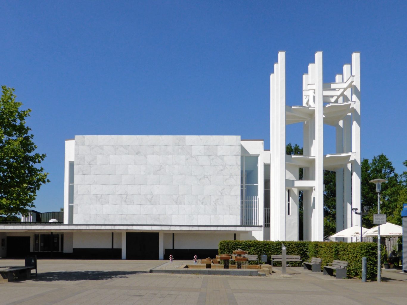 Stephanuskirche in Wolfsburg Moderne Architektur mit weißen Wänden, Türmchen und blauen Himmel im Hintergrund.